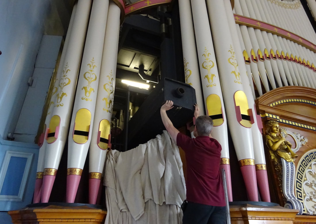 A team of organ builders get ready to return the pipe to its restored chest