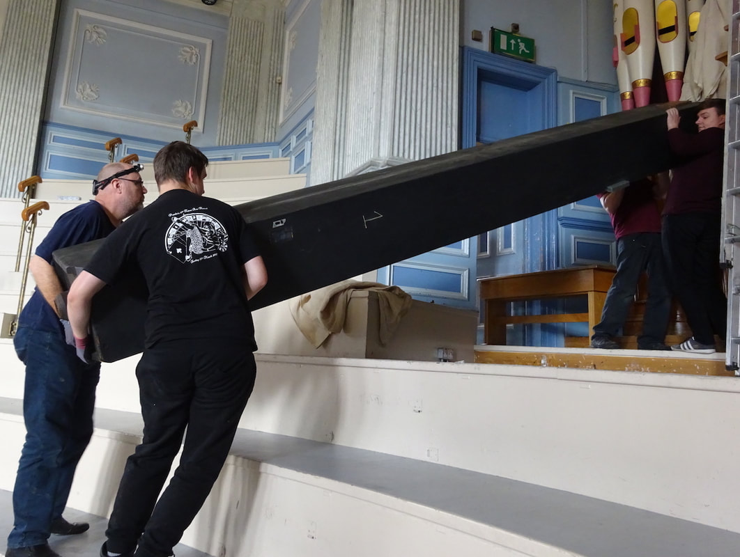 Organ builders gently move the organ pipe into the case